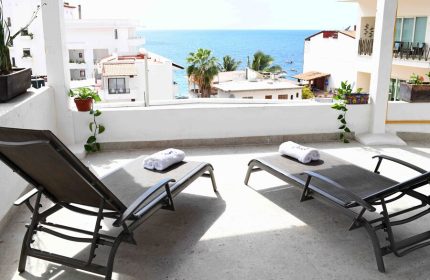 Petit Hotel Pilitas balcony with ocean view. Gay-friendly hotel offers sun loungers for relaxation. Ideal for gay men travel, vacation.