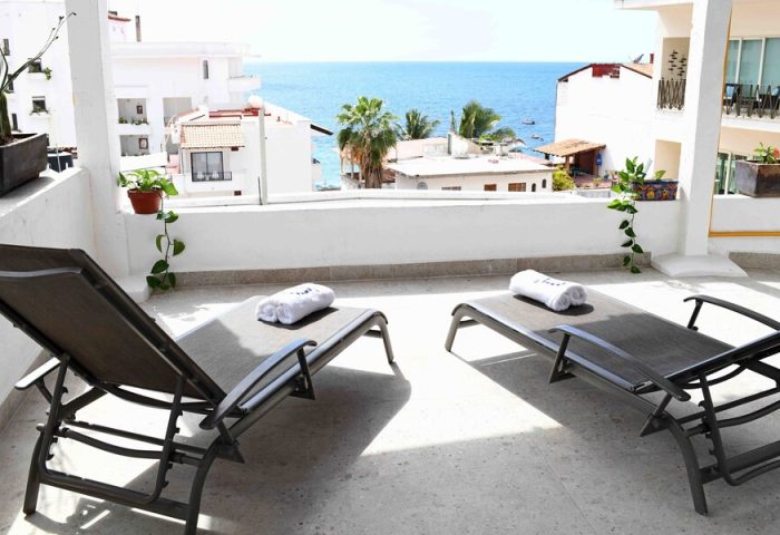 Petit Hotel Pilitas balcony with ocean view. Gay-friendly hotel offers sun loungers for relaxation. Ideal for gay men travel, vacation.
