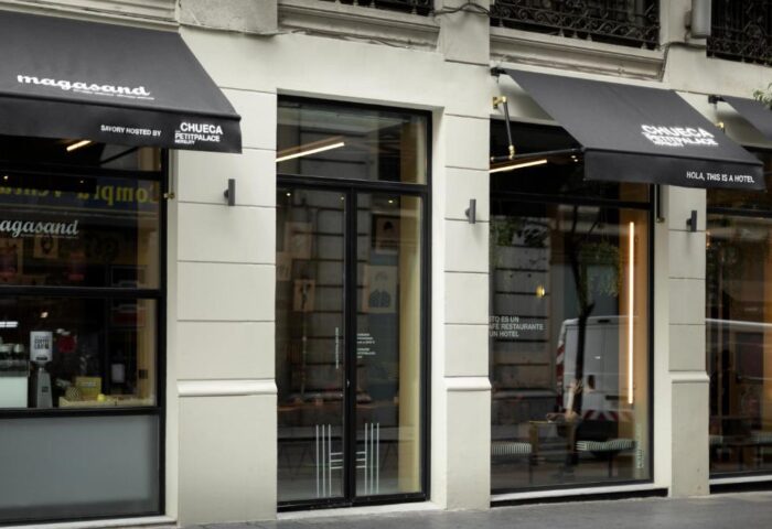 Petit Palace Chueca hotel facade. Gay-friendly hotel in Madrid's Chueca district. Modern design with awnings and glass windows. Stylish urban lodging.