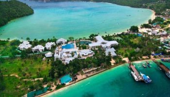 Aerial view of Phi Phi Island Cabana Hotel, a gay-friendly hotel, with turquoise waters, lush greenery, and boats docked at the pier.