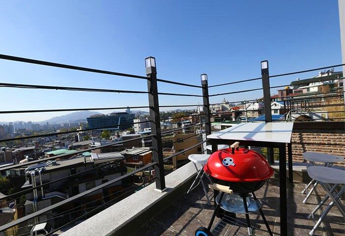 Philstay Itaewon Guesthouse's rooftop with a red grill, table and chairs. A gay-friendly hotel with city views, perfect for LGBTQ+ travelers in Seoul.