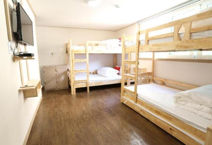 Philstay Itaewon Guesthouse: A gay-friendly hotel room featuring wooden bunk beds, lockers, and a TV. Great for gay travel in Seoul, South Korea.