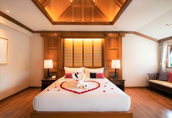 Gay-friendly Phra Singh Village hotel room with swan towels and rose petals on the bed. Romantic getaway for gay men in Chiang Mai.