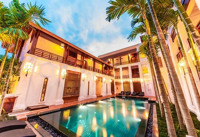 Phra Singh Village gay-friendly hotel pool view. A luxury resort with palm trees, balconies, and a swimming pool. Ideal for gay men travel.