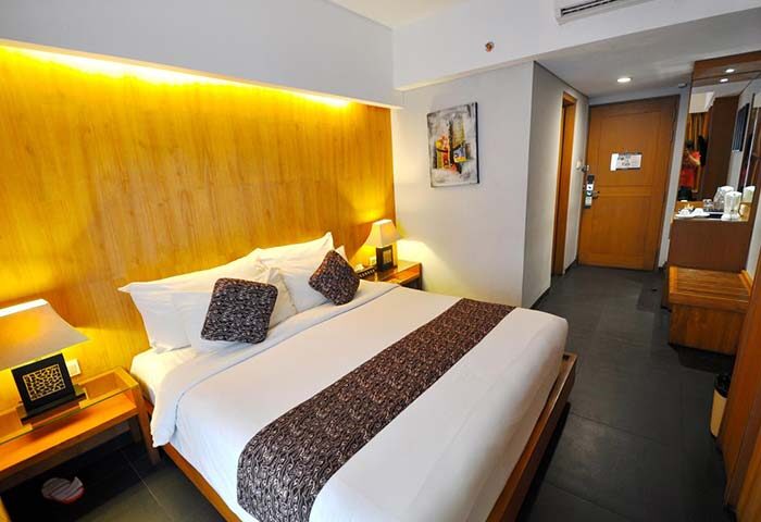 Ping Hotel Seminyak room. Gay-friendly hotel with a bed, bedside tables, lamps, and a painting. Modern design for gay travelers.