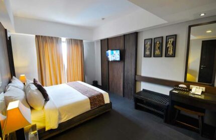 Ping Hotel Seminyak room. Gay-friendly hotel featuring a bed, TV, desk, and mirror. Modern design for gay travelers in Seminyak, Bali.
