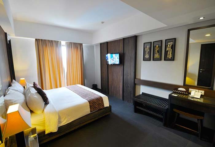Ping Hotel Seminyak room. Gay-friendly hotel featuring a bed, TV, desk, and mirror. Modern design for gay travelers in Seminyak, Bali.