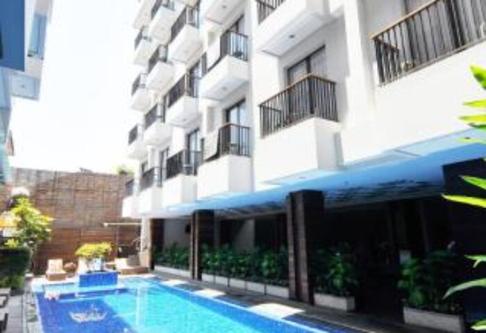 Ping Hotel Seminyak, a gay-friendly hotel. View of the building with balconies and a blue tiled pool. Ideal for gay men's travel in Seminyak.