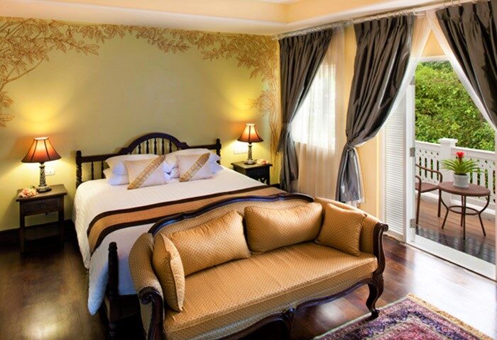 Ping Nakara Boutique Hotel and Spa room. Gay-friendly hotel with balcony, bed, and sofa. Luxury Chiang Mai travel for gay men.
