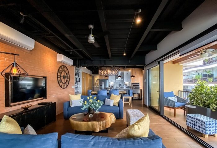 Pinnacle Resorts 179 Adults Only: Gay-friendly hotel living room with blue sofas, brick wall, and open kitchen. Balcony view.