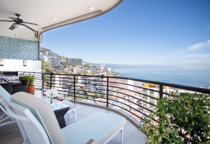 Balcony view at Pinnacle Resorts 180, a gay-friendly hotel. Ocean view with lounge chairs, table, and wine glasses. Perfect for gay travel.