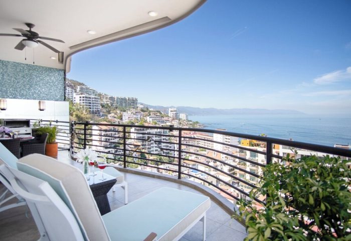 Balcony view at Pinnacle Resorts 180, a gay-friendly hotel. Ocean view with lounge chairs, table, and wine glasses. Perfect for gay travel.