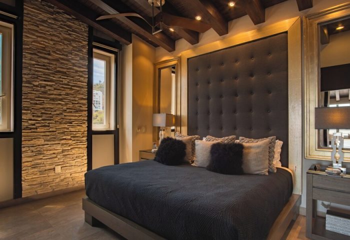 Pinnacle Resorts 180 gay-friendly hotel room. Luxurious bedroom with stone wall, dark headboard, and stylish decor. Gay travel lodging.