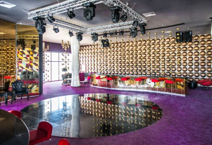 Platinum Yucatan Princess Adults Only Resort bar area. Gay-friendly all-inclusive suites and spa hotel with modern decor, red stools, and stage lighting.