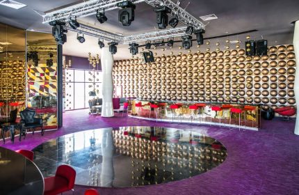 Platinum Yucatan Princess Adults Only Resort bar area. Gay-friendly all-inclusive suites and spa hotel with modern decor, red stools, and stage lighting.