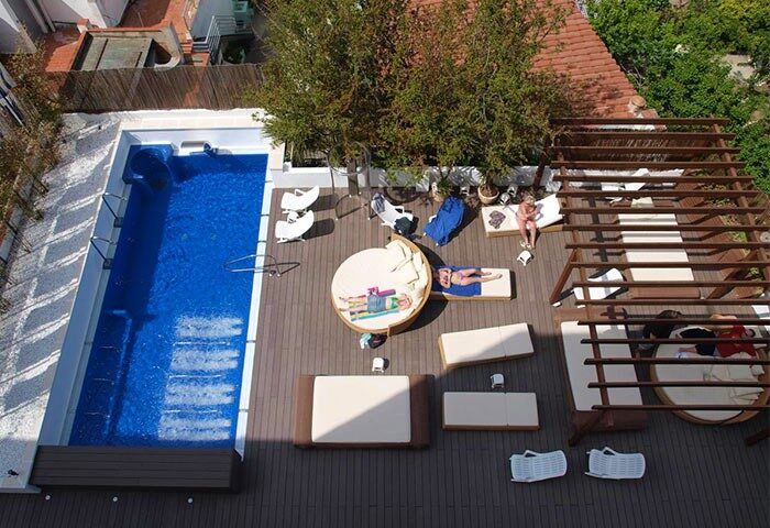 Gay-Friendly Hotel Platjador rooftop pool. Guests lounge on sunbeds. A modern, stylish space perfect for gay men's travel and relaxation.