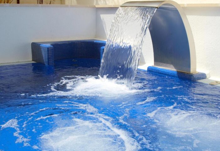 Platjador gay-friendly hotel detail: Waterfall feature into the blue pool. A relaxing spot for gay travelers to unwind and socialize.