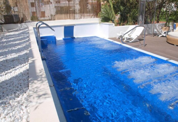 Pool at Gay-Friendly Hotel Platjador. Bright blue water, white stone accents, lounge chairs, and modern design. Perfect for a gay travel getaway.
