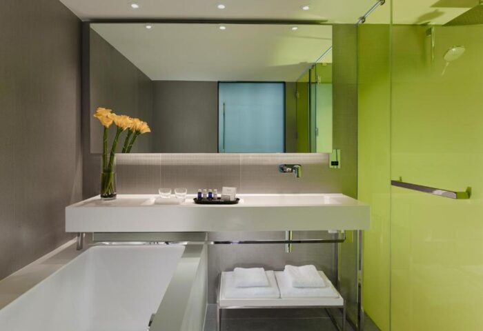 Park Plaza London Riverbank gay-friendly hotel bathroom. Modern design with white tub, sink, and green shower. Pet-friendly option.