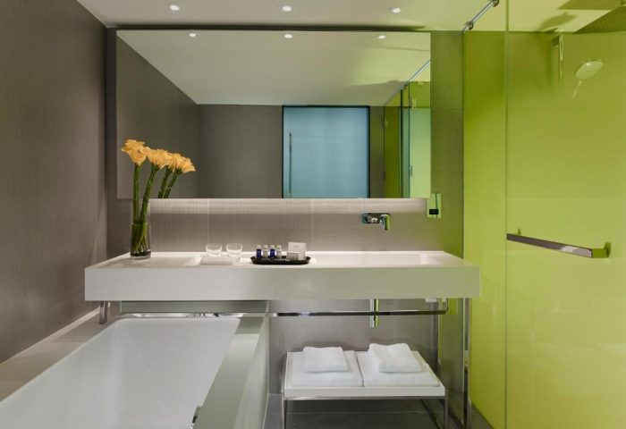 Park Plaza London Riverbank gay-friendly hotel bathroom. Modern design with white tub, sink, and green shower. Pet-friendly option.