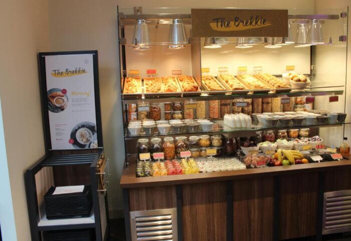 Breakfast buffet at Point A Hotel London Shoreditch, a gay-friendly hotel. The Brekkie sign, pastries, cereals, yogurt, and fresh fruit.
