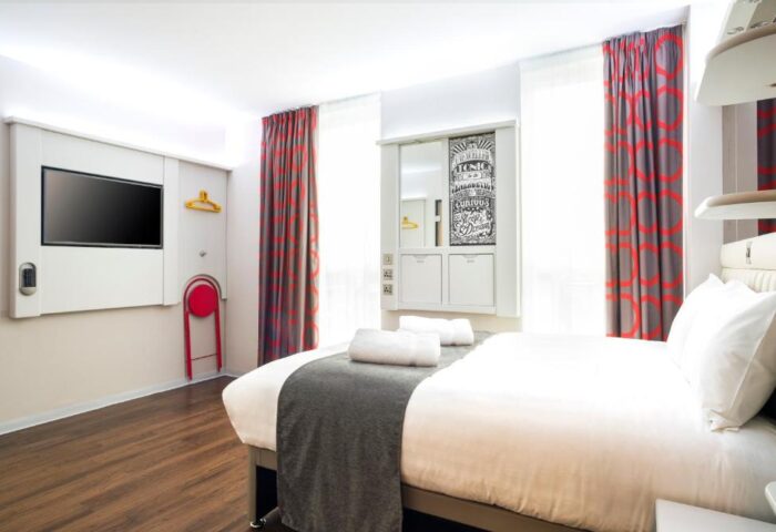 Point A Hotel London Shoreditch room. Modern design, white linens, TV, red accents. Gay-friendly hotel in Shoreditch, London. Comfortable stay.