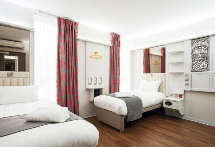 Point A Hotel London Shoreditch room with twin beds. Gay-friendly hotel with modern decor, red curtains, and wooden floor. Great for gay travel.