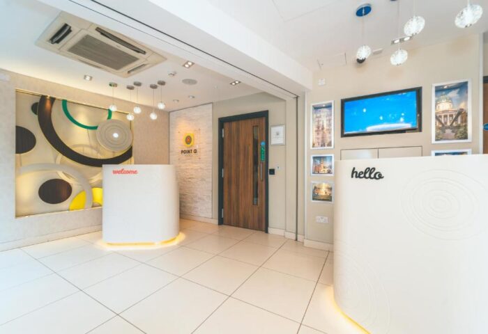 Point A Hotel London Westminster lobby with reception desks, modern decor, and bright lighting. Gay-friendly hotel for gay men travel.