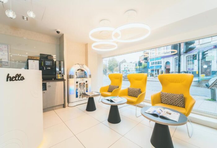 Point A Hotel London Westminster lobby. Yellow chairs, jukebox, and hello desk. Gay-friendly hotel with modern design for gay men travelers.