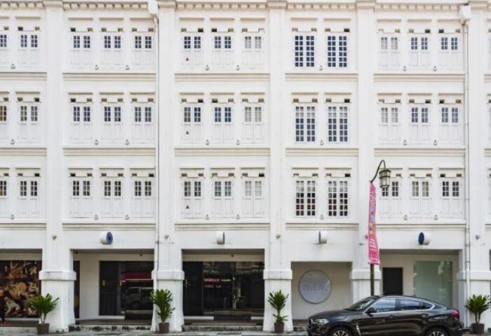 Porcelain Hotel by JL Asia, a gay-friendly hotel. Facade of the white building with windows, columns, and a car parked in front.