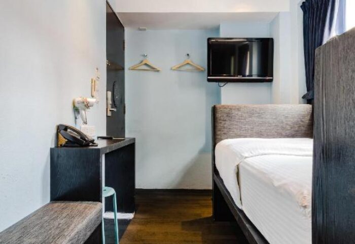 Porcelain Hotel room interior. Gay-friendly hotel by JL Asia features a bed, TV, desk, and minimalist decor for comfortable gay travel.