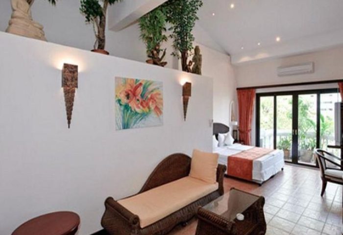 Poseidon Boutique Hotel room. Gay-friendly hotel with wicker furniture, a painting, plants, and a balcony. Comfortable and inviting.