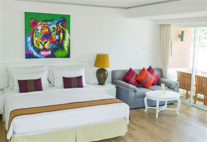 Pride Beach Resort adults-only room. Gay-friendly hotel room with bed, couch, and colorful tiger art. Modern room at gay beach resort.