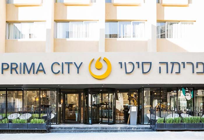 Prima City Hotel Tel Aviv entrance. Gay-friendly hotel featuring a revolving door, plants, and a modern design. Ideal for gay travel.