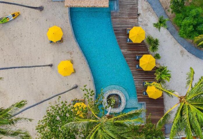 Aerial view of Princess Paradise Koh Phangan, a gay-friendly hotel. Features a pool, beach, umbrellas, and tropical scenery.
