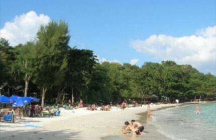 Beach view at gay-friendly Pudsa Bungalow. People relax on the sand, swim in the sea. A tropical paradise for gay men's travel.