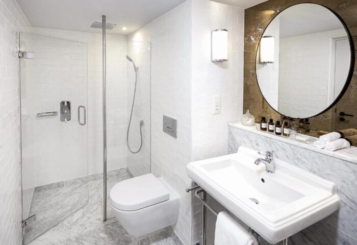 Bathroom at the Gay-Friendly Pulitzer Amsterdam Hotel. Features a shower, toilet, sink, and round mirror. Ideal for gay men travelers.