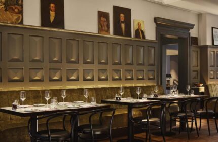 Pulitzer Amsterdam gay-friendly hotel restaurant. Tables set for dining, portraits on the wall, and a sophisticated ambiance. Fine dining.