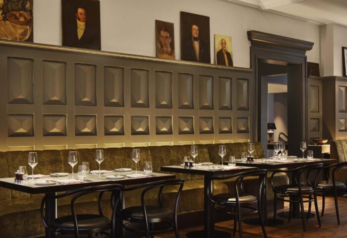 Pulitzer Amsterdam gay-friendly hotel restaurant. Tables set for dining, portraits on the wall, and a sophisticated ambiance. Fine dining.