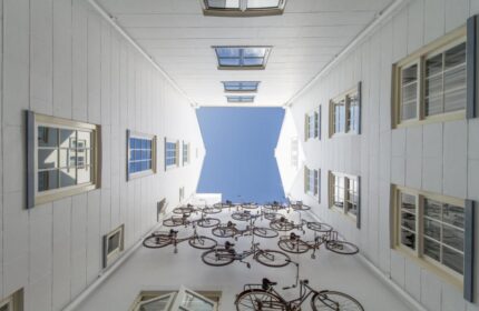 Unique bike art installation at Pulitzer Amsterdam, a gay-friendly hotel. View looking up at bikes on white walls and blue sky.