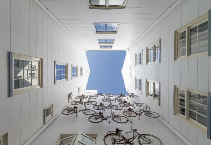 Unique bike art installation at Pulitzer Amsterdam, a gay-friendly hotel. View looking up at bikes on white walls and blue sky.
