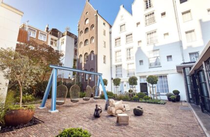 Pulitzer Amsterdam gay-friendly hotel courtyard. Egg-shaped swings hang over brick ground. Unique building architecture in Amsterdam.
