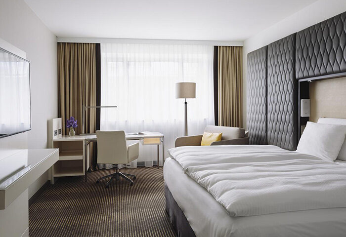 Pullman Berlin Schweizerhof Hotel room. Gay-friendly hotel with bed, desk, chair, and modern decor. Comfortable stay in Berlin.
