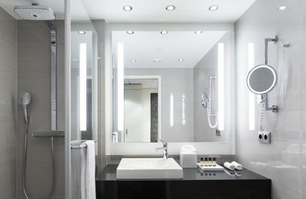 Bathroom at Pullman Berlin Schweizerhof Hotel, a gay-friendly hotel. Features a shower, sink, mirror, and toiletries. Modern design.