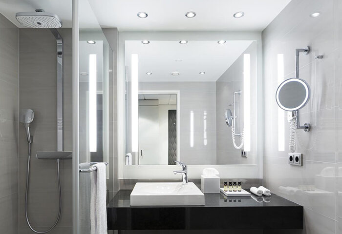 Bathroom at Pullman Berlin Schweizerhof Hotel, a gay-friendly hotel. Features a shower, sink, mirror, and toiletries. Modern design.