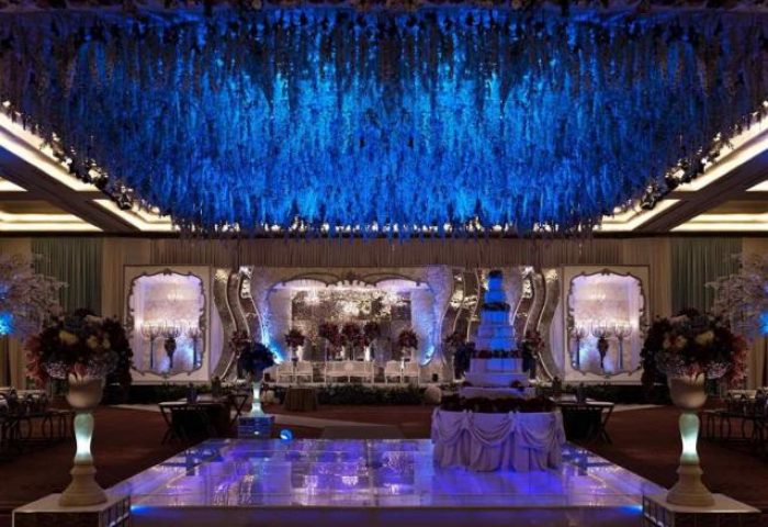Pullman Jakarta Central Park Hotel ballroom with blue lighting, stage, and cake. Gay-friendly hotel for weddings and events.