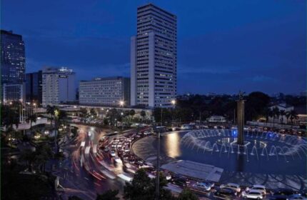 Night view of Pullman Jakarta Indonesia, a gay-friendly hotel, with the Welcome Monument fountain and city skyline. Jakarta travel.