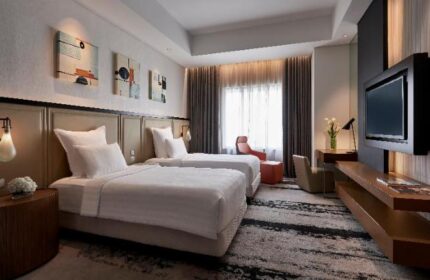 Gay-friendly Pullman Jakarta Indonesia hotel room with twin beds, TV, desk, and modern decor. Ideal for gay travelers in Jakarta.