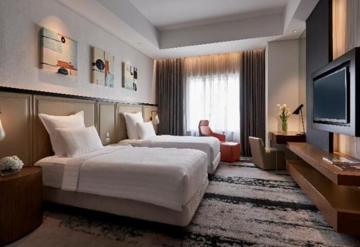 Gay-friendly Pullman Jakarta Indonesia hotel room with twin beds, TV, desk, and modern decor. Ideal for gay travelers in Jakarta.