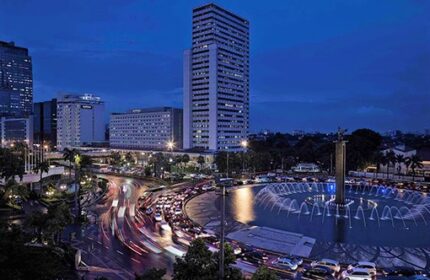 Pullman Jakarta Indonesia, gay-friendly hotel. Night view of the city with a fountain, skyscrapers, and traffic. Gay travel advice.